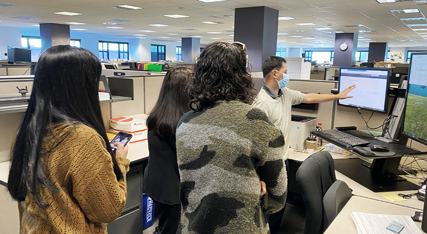 A person in an office showing their screen to a team of people. 