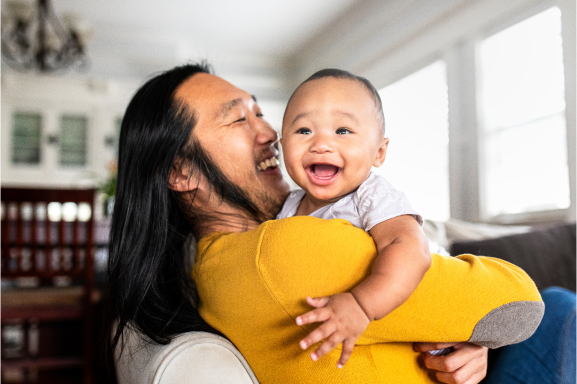 A smiling man holding a happy baby