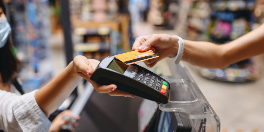 A customer tapping a card at a point of sale terminal