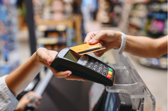 A customer tapping a card at a point of sale terminal